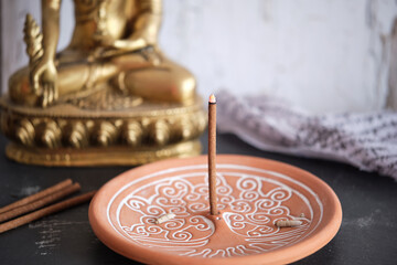 Tibetische Räucherstäbchen auf rundem Halter Yggdrasil mit goldenem Buddha (Close-up)