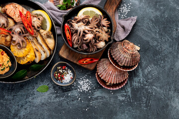 Grilled seafood variety with vegetables on dark background.