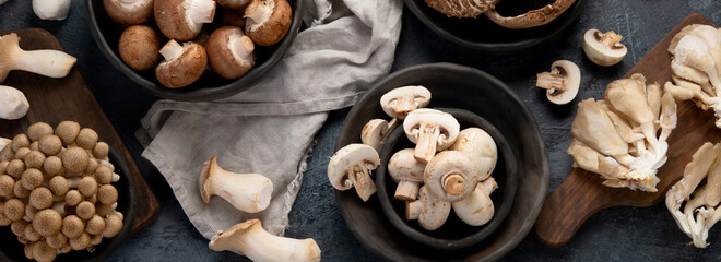 Variety of raw mushrooms on dark background. Vegan food cocnept. Top view, flat lay, copy space