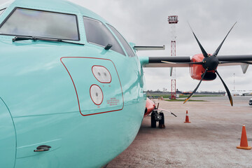 Fototapeta na wymiar Orange and blue colored. Turboprop aircraft parked on the runway at daytime
