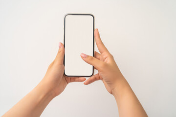 Closeup shot of a woman typing on mobile phone isolated on white background.. Girl's hand holding a modern smartphone and pointing with figer. Blank screen