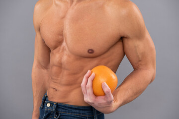 Fit man cropped view with six pack abs muscular torso hold orange fruit as dieting symbol, vitamin c