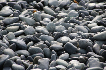 Obraz premium Round stones on a dry river bed outside in nature. Smooth pebbles with light gray tones in ambient light.