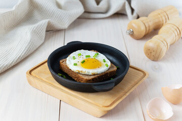 Toast with fried egg and green onions in a cast-iron skillet.