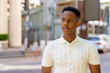 Fototapeta premium Portrait of young African businessman wearing casual clothes at city street while thinking