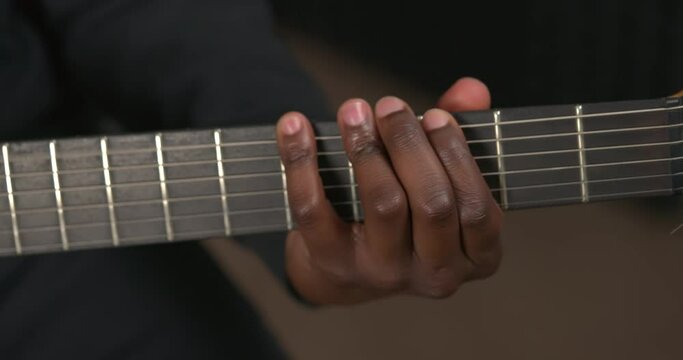 Close up of electric guitar neck. Unrecognizable African man making chord on fingerboard