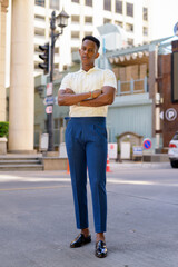 Full length shot of young African businessman outdoors in city streets looking at camera with arms crossed