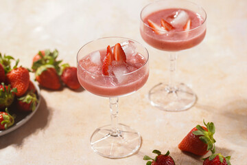 Two glasses with red strawberry dessert with ice cubes and crashed ice and strawberry slices