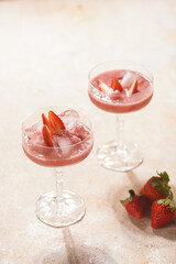 Two glasses with red strawberry dessert with ice cubes and crashed ice and strawberry slices