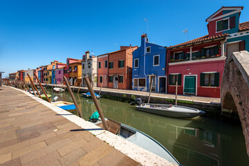 Fototapeta na wymiar Multi colored houses and moored small boats along a canal in Burano island, Venice lagoon, UNESCO world heritage site, Veneto, Italy, Europe. 