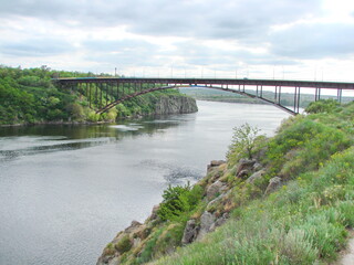 Fototapeta premium View from the top of the hill, covered with dense spring vegetation, on the shiny water surface of the Dnieper coast.