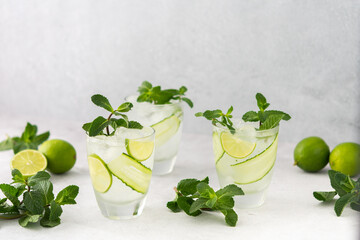 Cold refreshing drinks with lime and cucumber, summer iced beverage and fresh green mint, glasses with lemon water