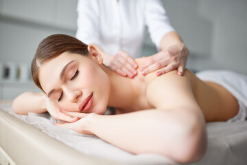Fototapeta na wymiar Young woman enjoying classic back massage by professional female therapist or masseur