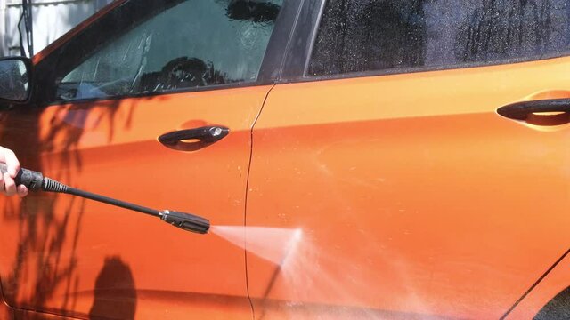 Manual car wash with pressurized water in car wash outside in summer.