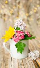 Naklejka na ściany i meble White cup with colorful flowers on wooden background