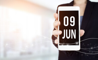 June 9th. Day 9 of month, Calendar date. White smartphone with Calendar date in businesswoman hand...