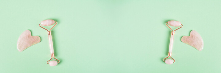 Roller and gua sha facial massage tools on a green background. Skin care, beauty and health concept. Banner
