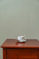 Fototapeta na wymiar Single white cup of tea on dark wooden table. Morning breakfast concept. Minimalism life style. Light grey wall background.