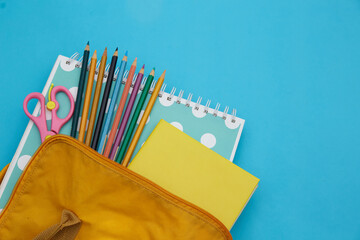 Backpack with school stationery on blue background . Back to school concept 
