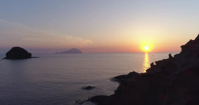 Time lapse of Salina coast in Aeolian islands during a summer sunset. Silhouette of Salina coast, blue and orange sky with clouds in background and sea during golden hour.