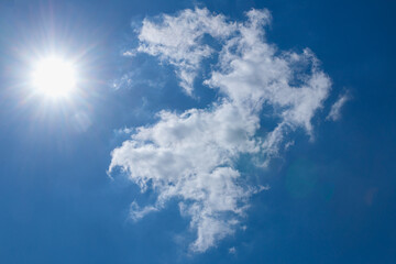 Naklejka na ściany i meble Sunbeams in summer with white clouds on a blue sky background