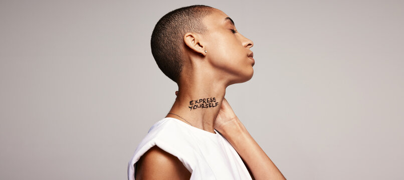 Shaved head woman with express yourself written on her neck