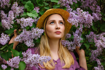 Close up beauty portrait of young beautiful happy smiling woman with healthy flawless radiant skin, natural makeup, posing with blooming lilac flowers. Copy, empty space for text.