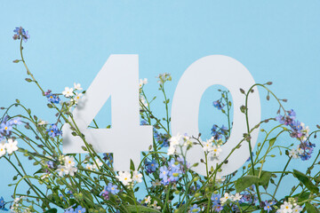 Number forty among blue forget-me-not flowers. .Birthday, anniversary, jubilee concept.