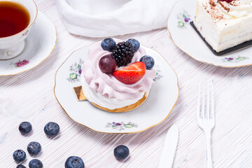 Piece of berry cake decorated with fresh berries on wooden background