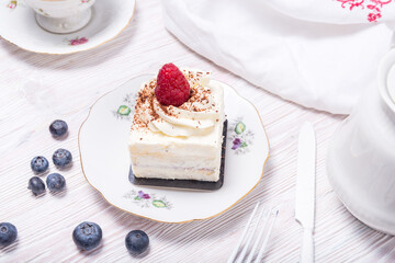 Piece of berry cake decorated with fresh berries on wooden background