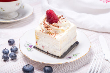 Piece of berry cake decorated with fresh berries on wooden background