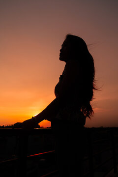 Photo of silhouette adult woman in profile on twilight background. Lonely woman standing alone moments sunset