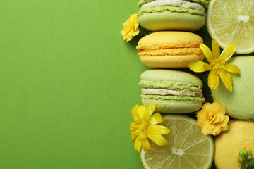 Macaroons, limes and flowers on green background
