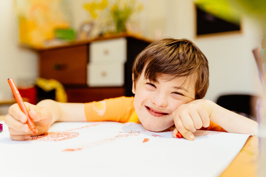 Young boy disabilities Or Down's syndrome learning about painting watercolor and bright smile for active learning and encouraging beside. Education and special child concept.