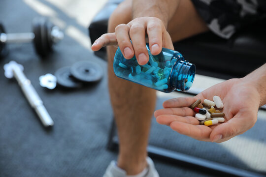 Sportsman with bottle of pills in gym, closeup. Doping concept