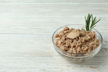 Bowl with canned tuna on white wooden background