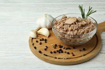 Bowl with canned tuna on white wooden background