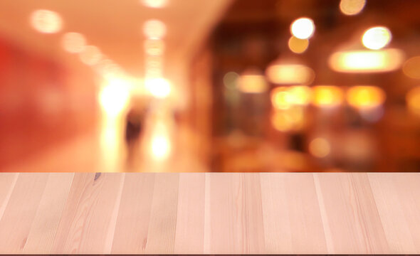 Close Up Wooden Table Top In Front Of Abstract Bokeh Blur Background, .hallway In Shopping Mall, And Ice Cream Shop On Right Side In Shopping Mall.