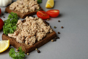 Sandwiches with canned tuna and ingredients on gray background