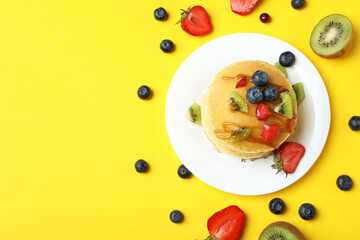 Concept of delicious dessert with pancakes on yellow background