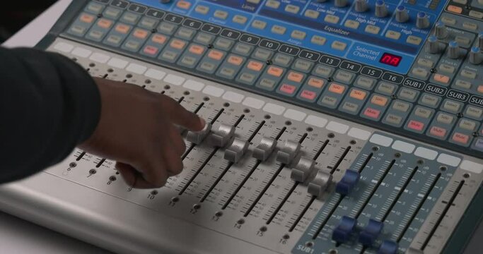 Man's hand using audio mixing console. Adjusting volume of sound. Professional studio equipment