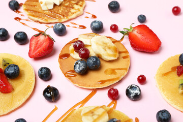 Concept of delicious dessert with pancakes on pink background