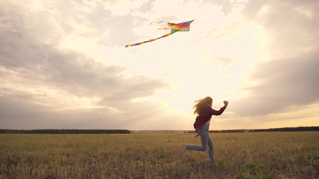Happy child is dream. girl runs across field with flying toy in her hands. Kite on background of sky. Silhouette of child running across the field with kite. Happy concept of dream of bank.