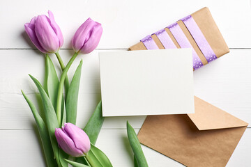Empty card with copy space, gift box and tulip flowers bouquet on white wooden background, mockup