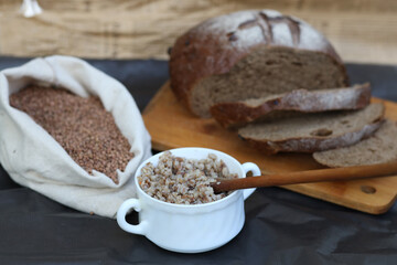 Flat lay composition with bowl of buckwheat flour, grains and bread on grey table