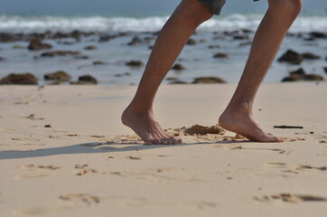 male foots or feet running gesture in the beach with blurred sea background
