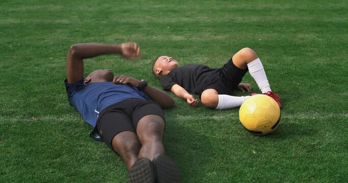 Diverse father and son looking at sky after football training
