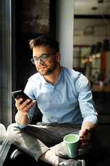 Young businessman drinking coffee in her office. Handsome man on coffee break..