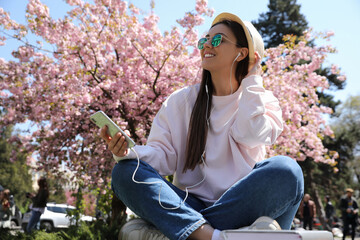 Young woman listening to audiobook in park