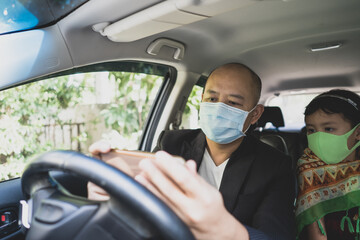young man sitting in car with daughter and wearing healthy face mask.